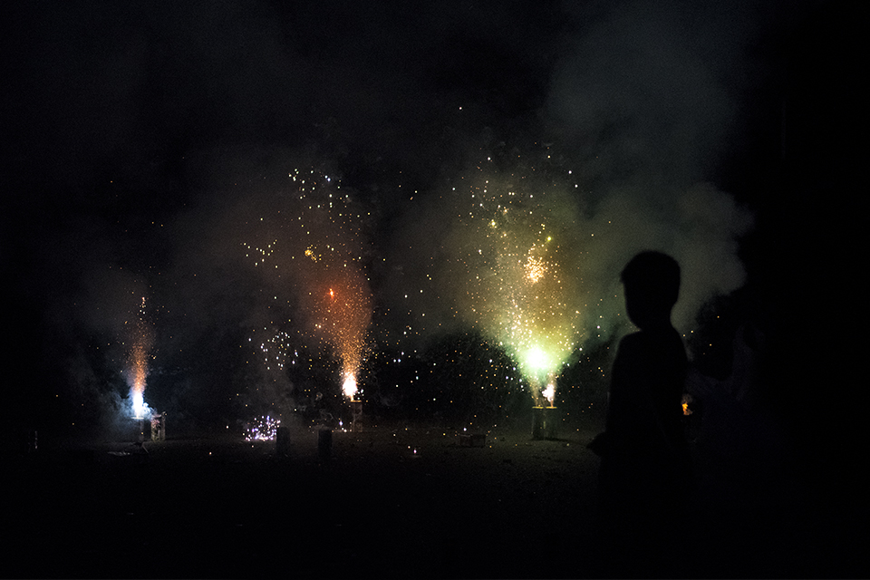 Silhouette of a boy over ground sparklers in the dark